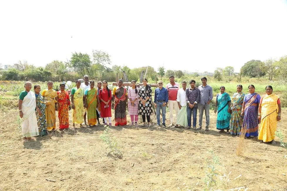Villagers standing in a long line at the edge of a field