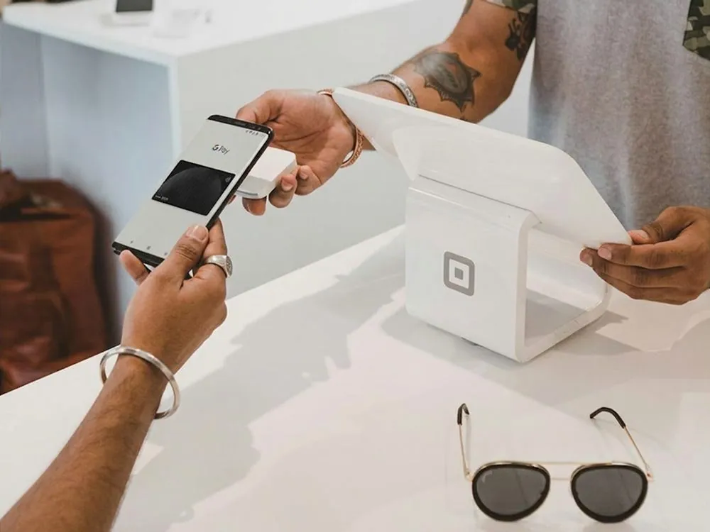 Hands tapping a card on a payment reader