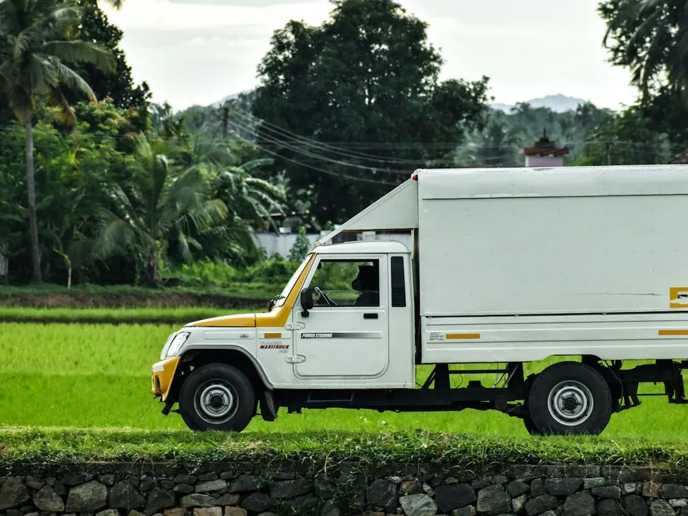 A delivery truck on a track beside paddy fields