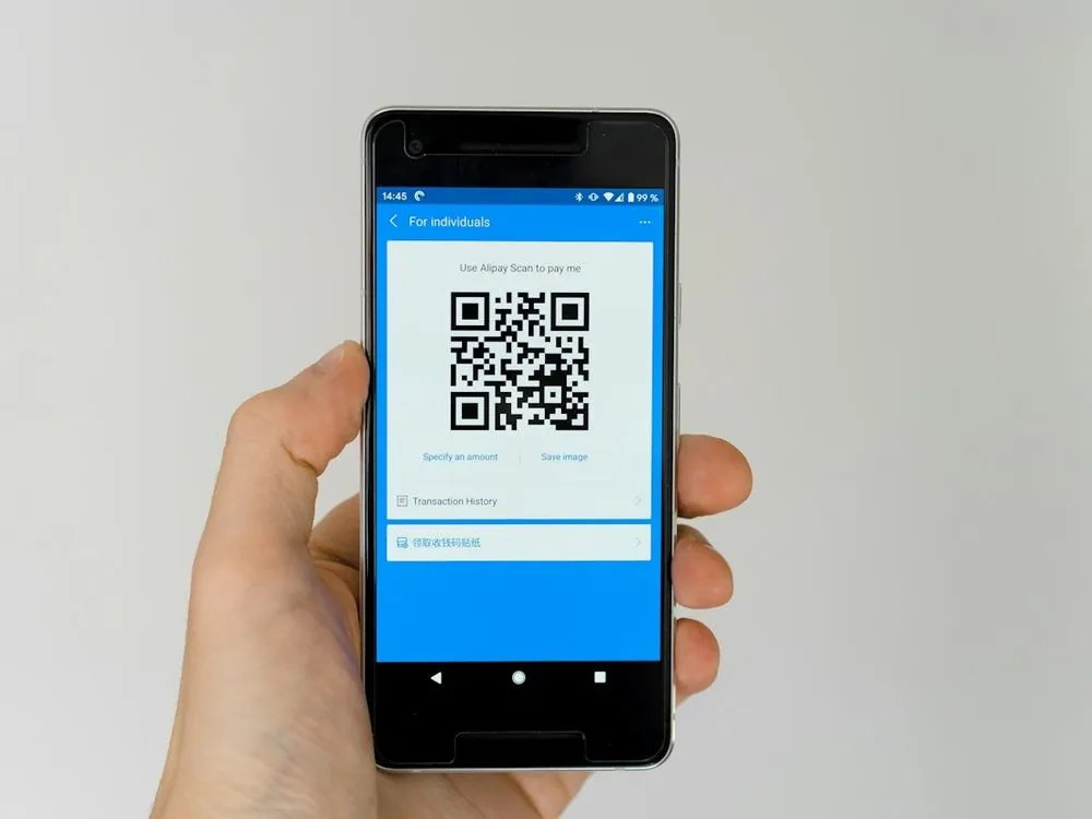 A hand holding a phone showing a QR code