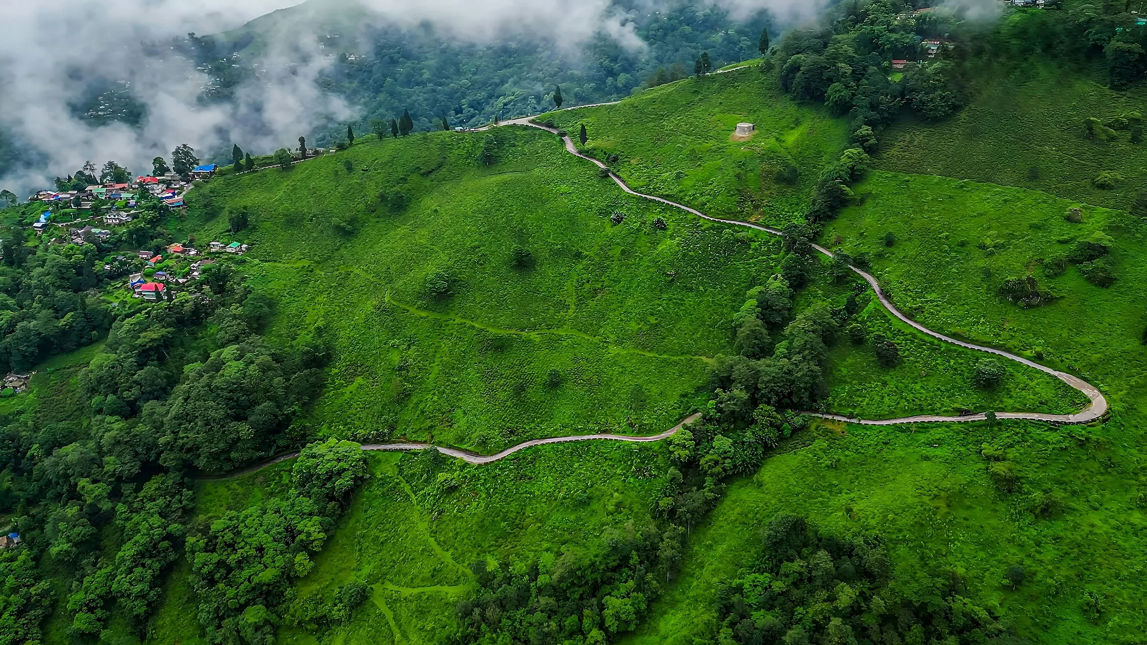 A road winding through green hills, from the air