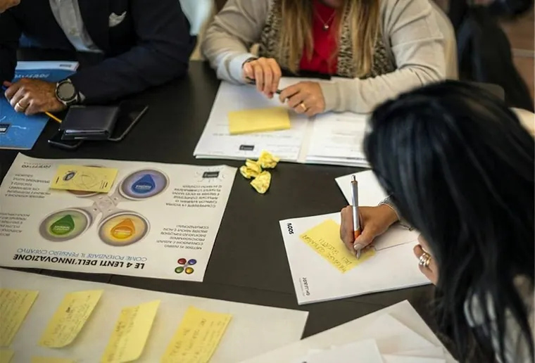 Hands around a table of printed charts and sticky notes