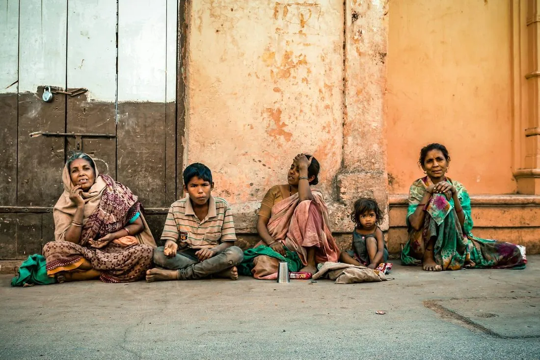 A family sitting together on the ground outside their house