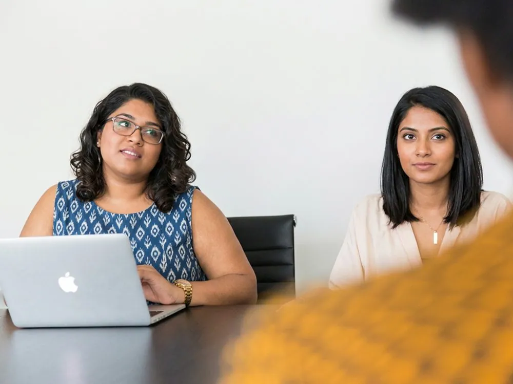 Two women talking over a laptop