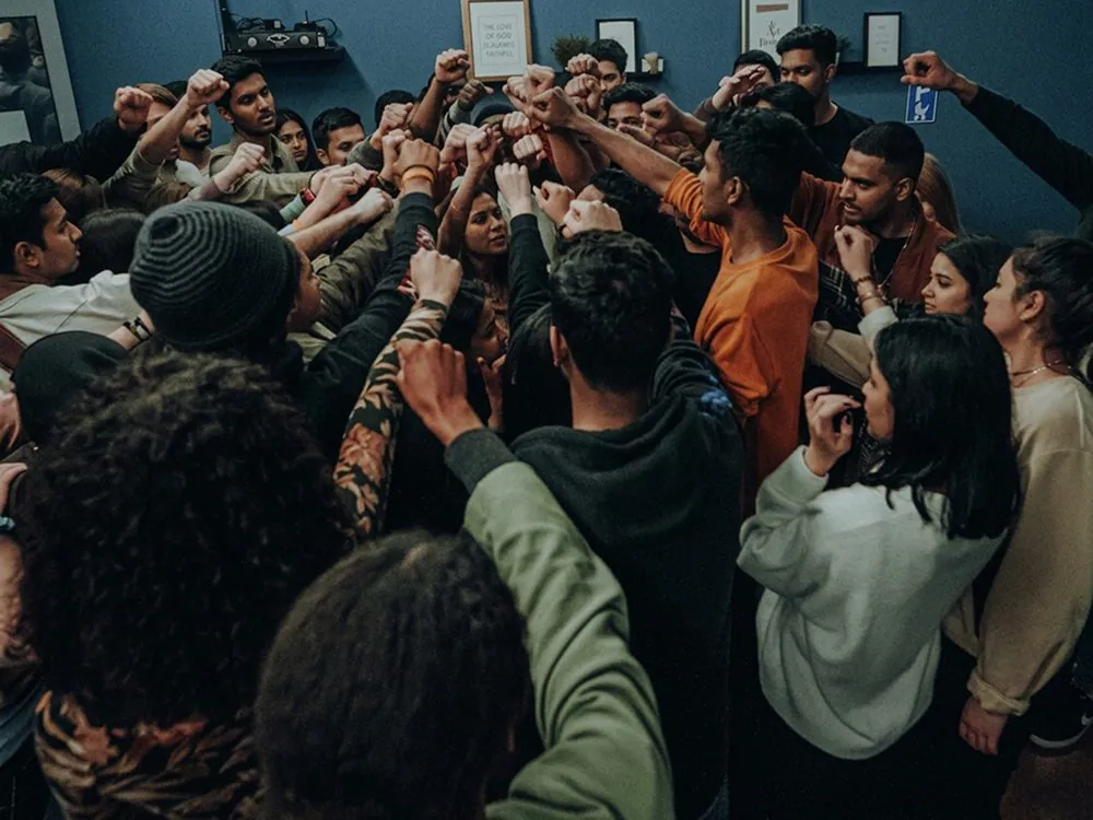 A crowd of young people with their hands raised