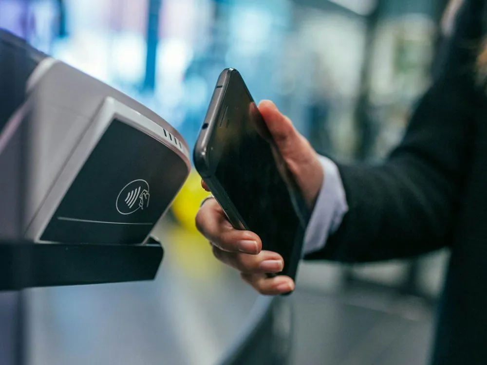 A hand holding a phone to a card machine