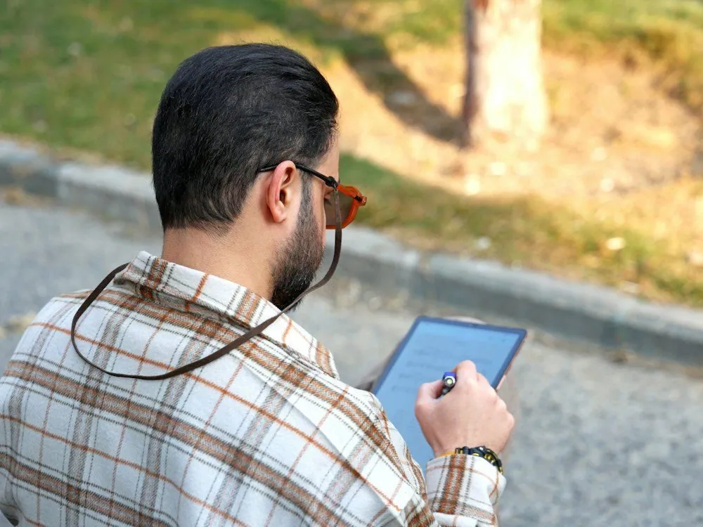 A man outdoors looking at a tablet