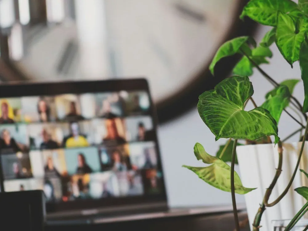 A laptop showing a grid of faces on a video call