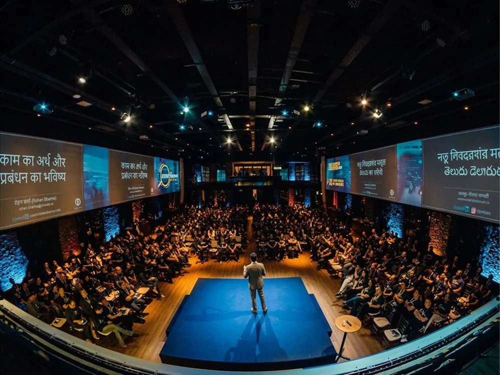 A speaker on stage before a full auditorium