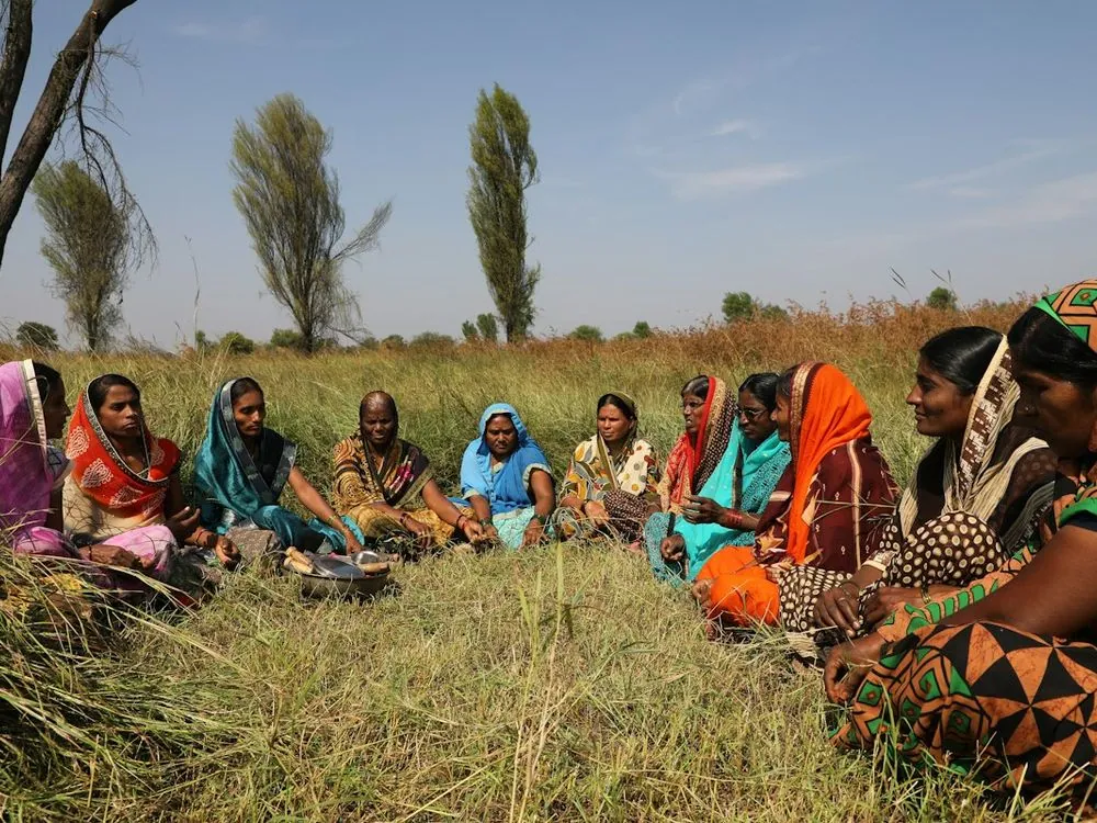 Women seated in a circle for a group meeting in a field
