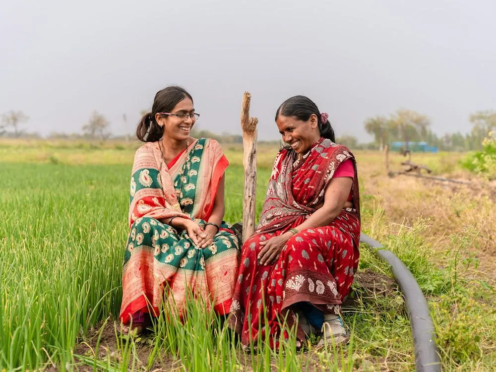Two women sitting on a bund beside a paddy field
