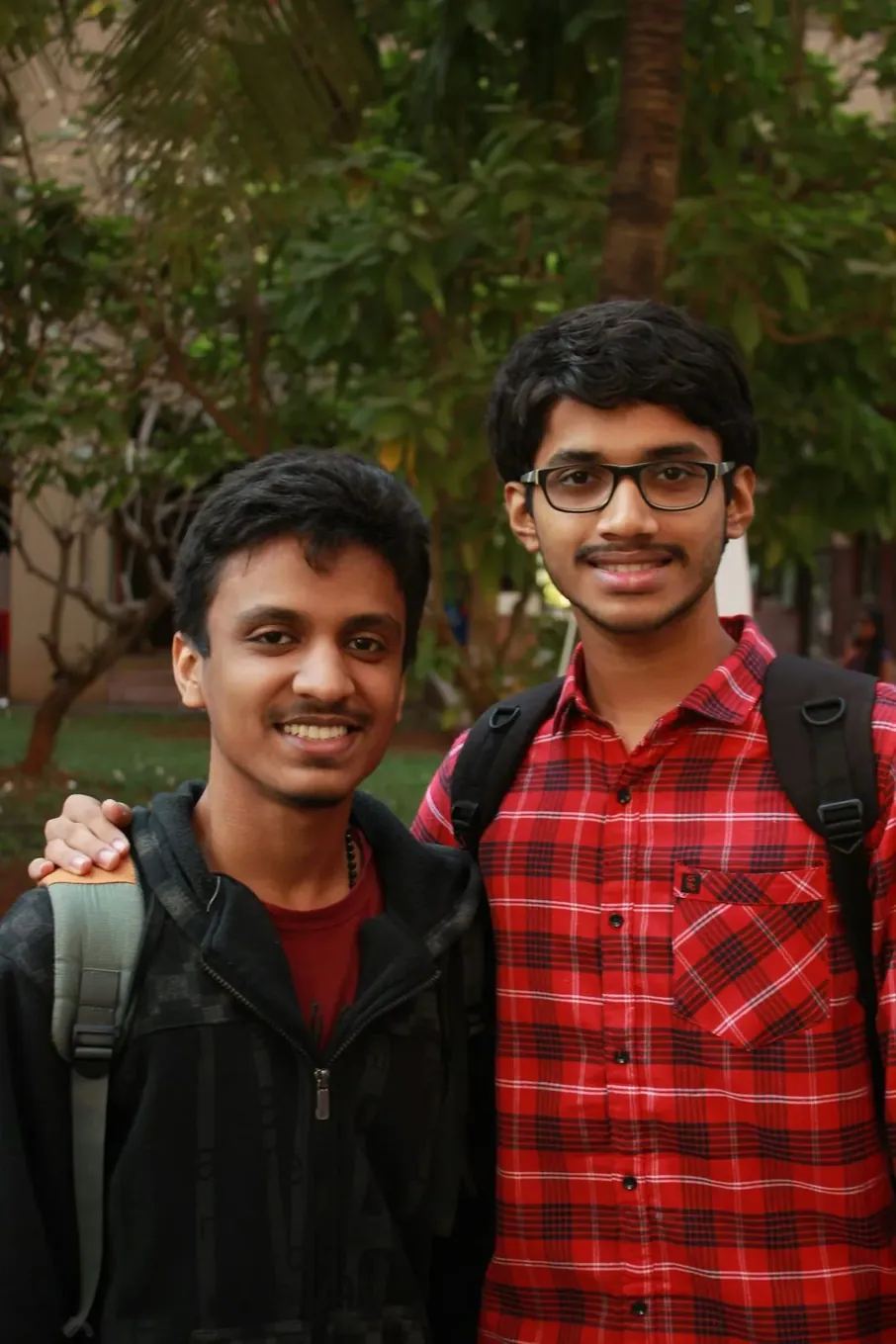 Two students smiling, one carrying a backpack