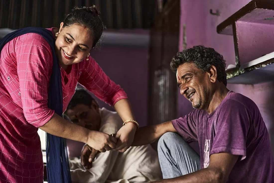 A man smiling as a health worker checks him over