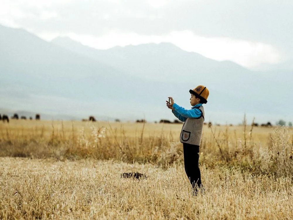 A person standing alone in a field, hills behind
