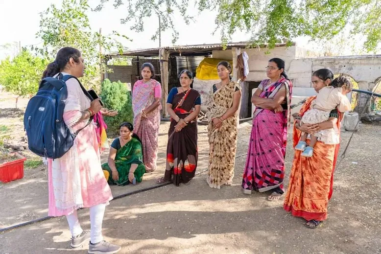 Women standing together, a girl with a blue backpack among them