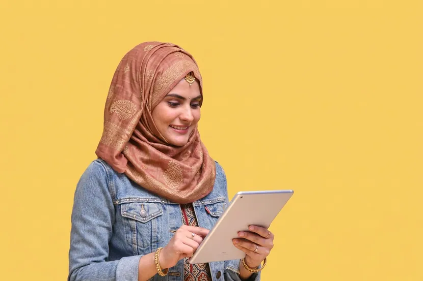A woman holding a tablet against a yellow wall