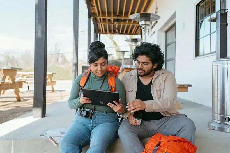 Two people looking at a tablet on a bench