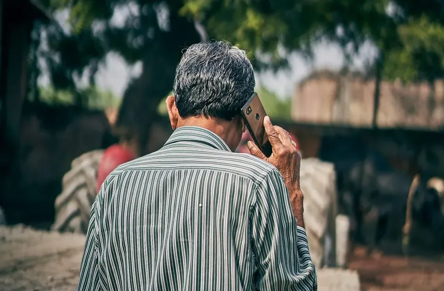 A farmer on the phone beside his tractor