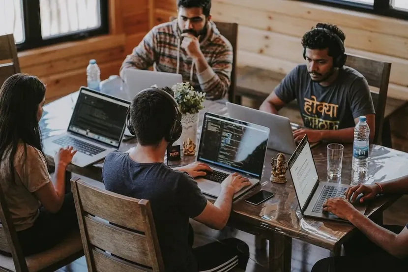 People working at laptops along a long table