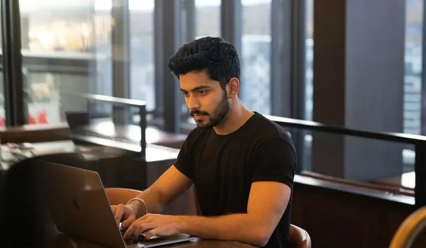 A man working at a laptop by a window