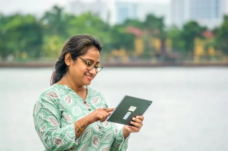 A woman with a tablet beside the water