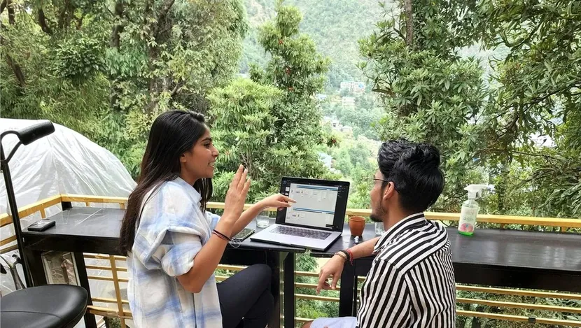 Two people working at a laptop on a terrace