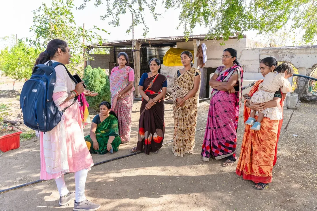 Women in a village lane, one carrying a backpack