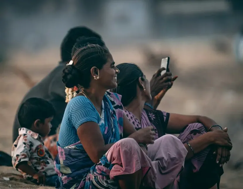 Women sitting outside, one holding a phone up