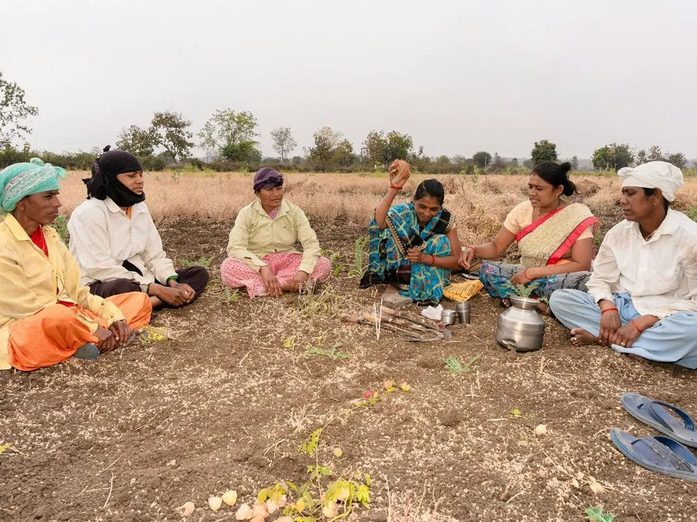 Farmers seated on the ground in a field