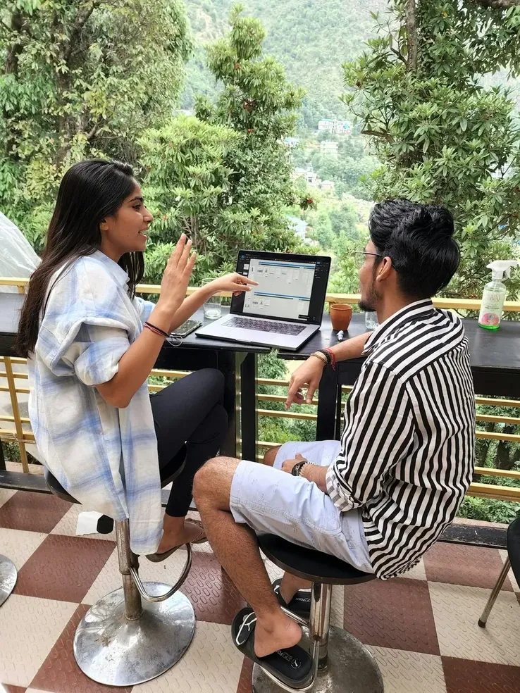 Two people working at a laptop on a terrace