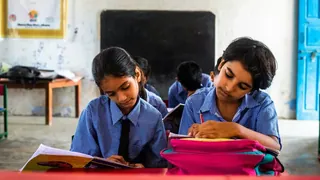 Two girls writing at their desk in class